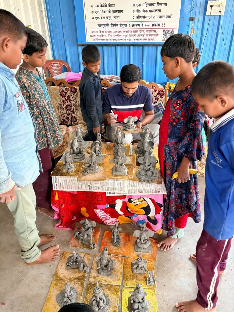 Committee members guiding children as they make Ganpati idols